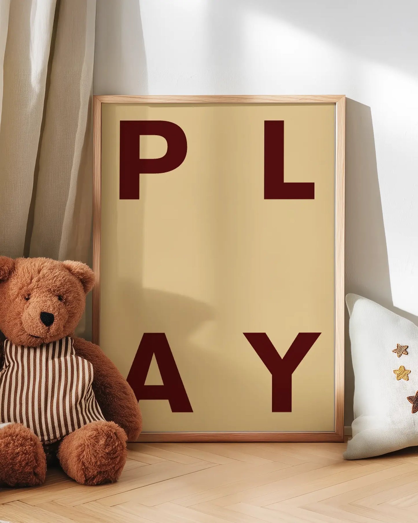Poster with 'PLAY' letters next to a teddy bear on a wooden floor.