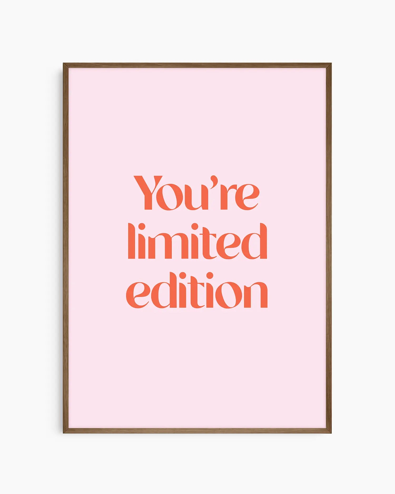 Children's poster with red text 'You're limited edition' on a pink background framed in a dark oak frame.