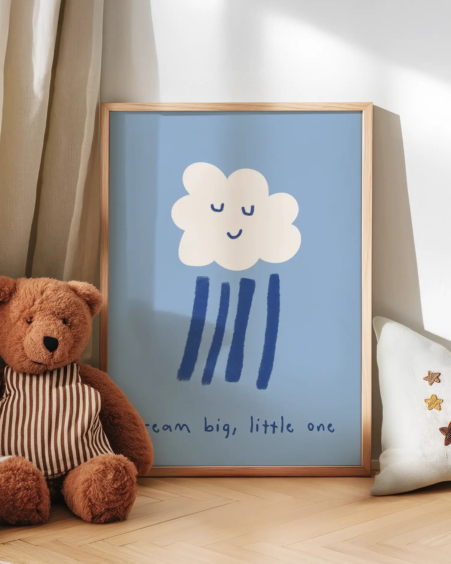 Artwork with a cloud and raindrop design next to a teddy bear on a wooden floor.