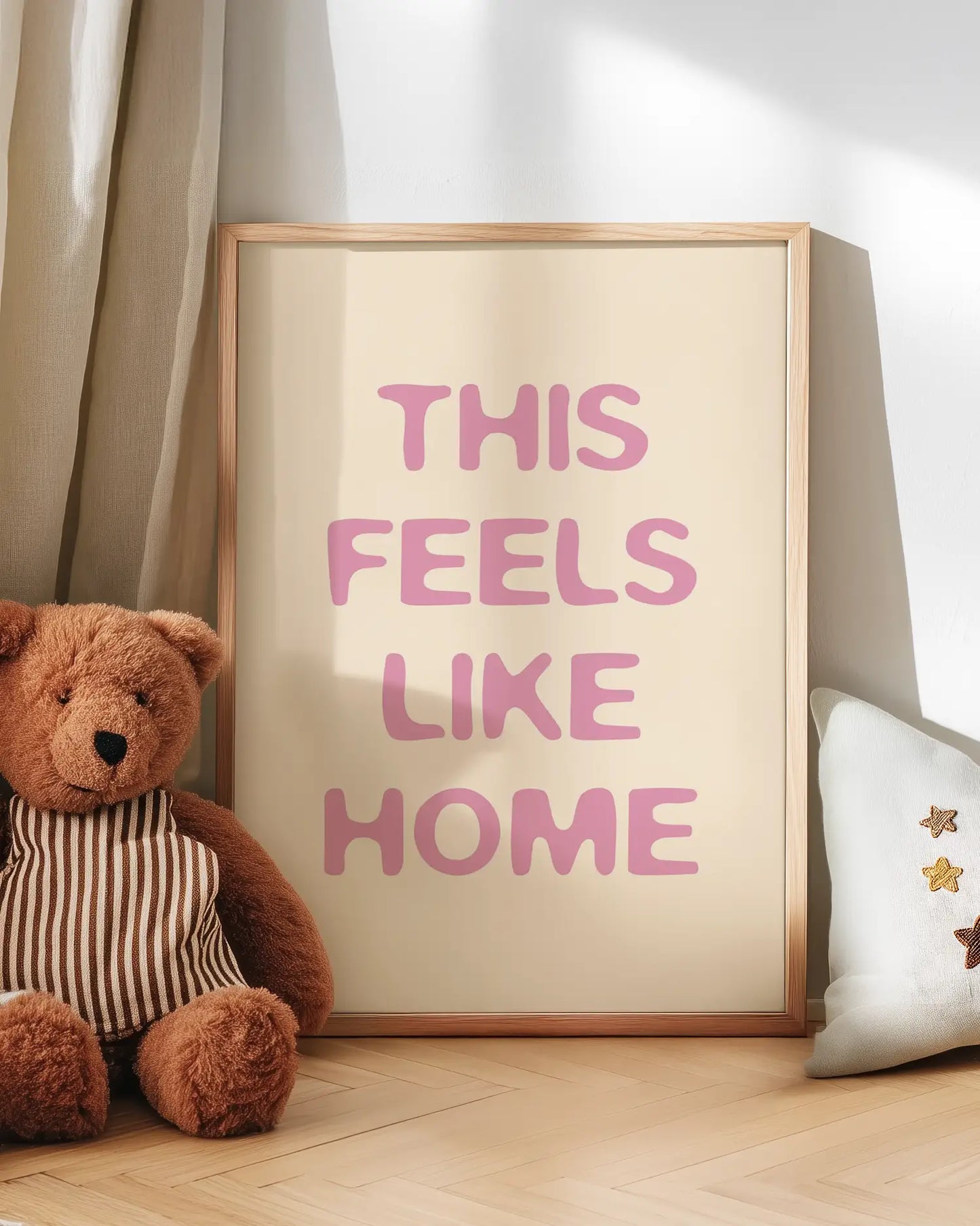 Artwork with 'THIS FEELS LIKE HOME' text next to a teddy bear on a wooden floor.