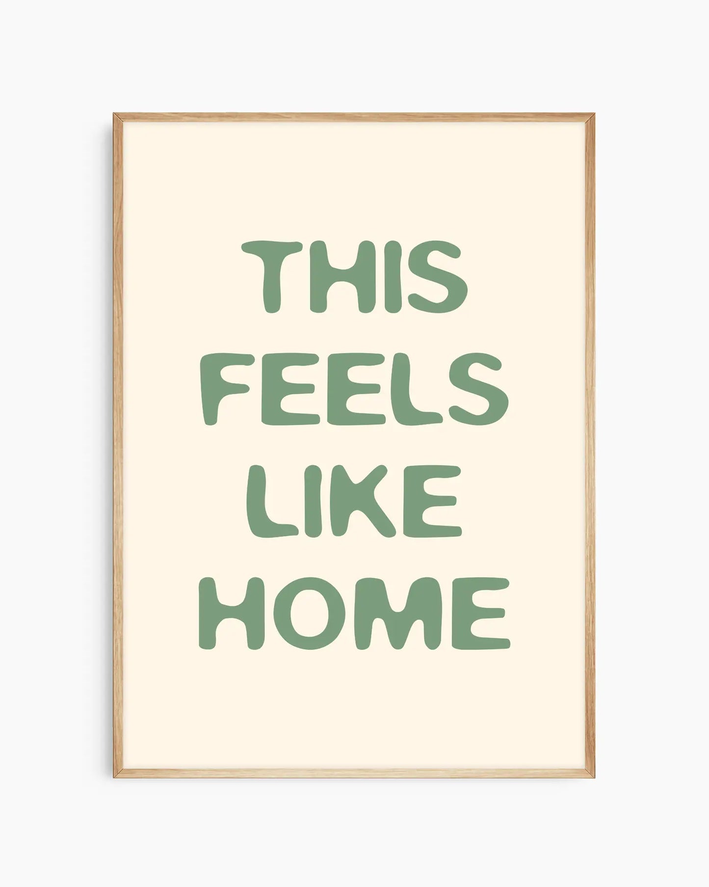 Nursery poster with the text 'This feels like home' written in green, inserted in an oak frame