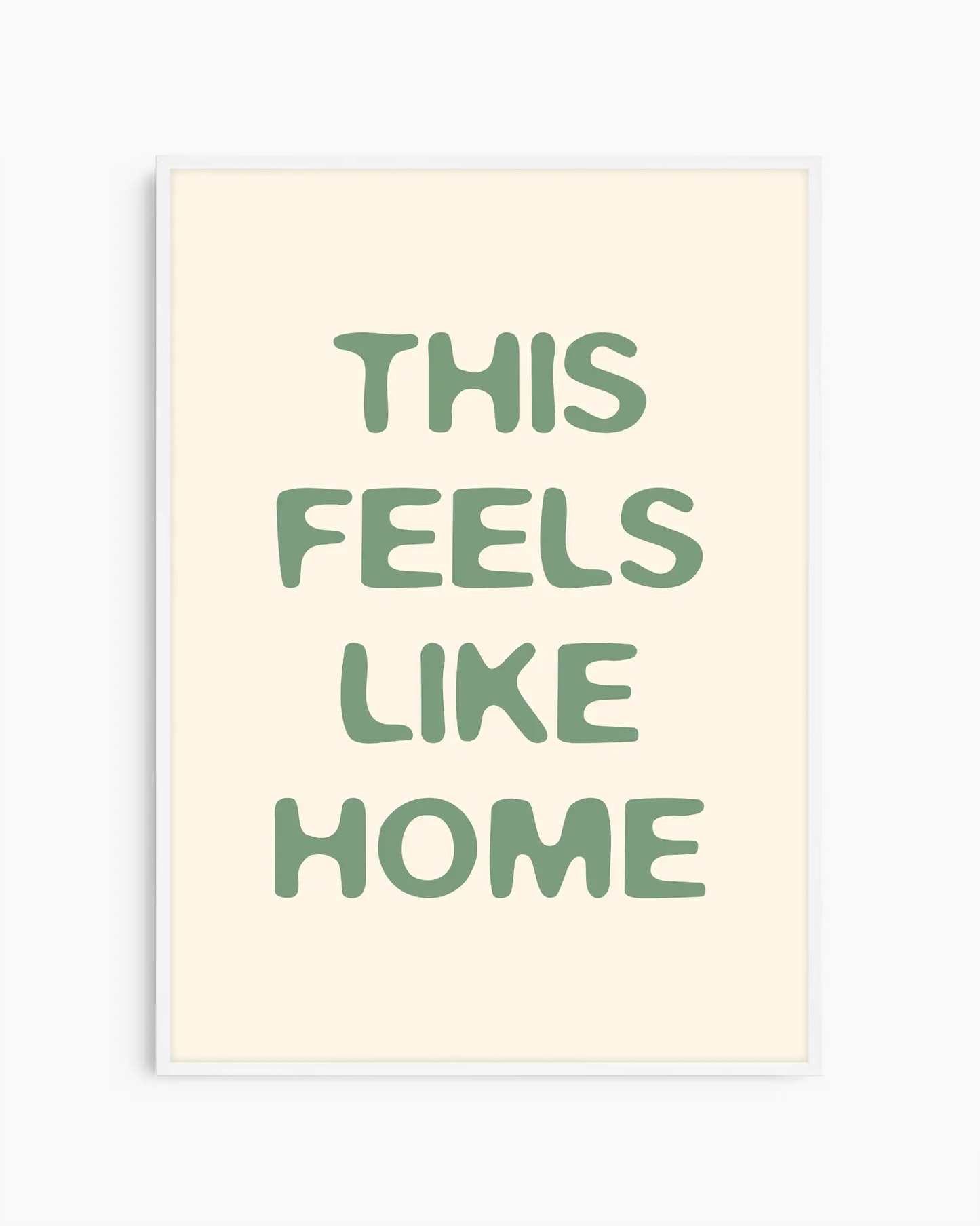 Nursery poster with the text 'This feels like home' written in green, inserted in a white wooden frame