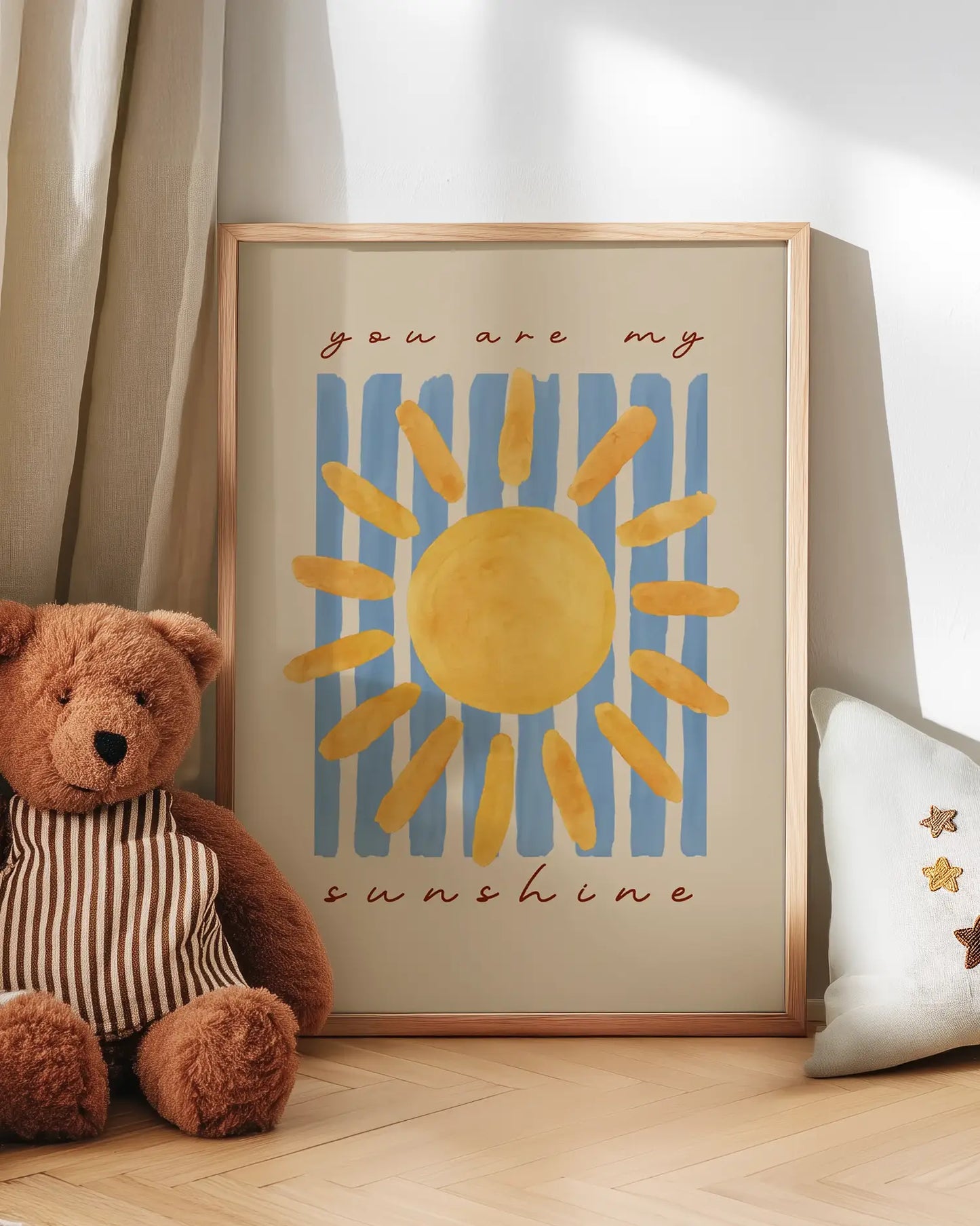 Artwork with sun design and 'you are my sunshine' text, next to a teddy bear and pillow.