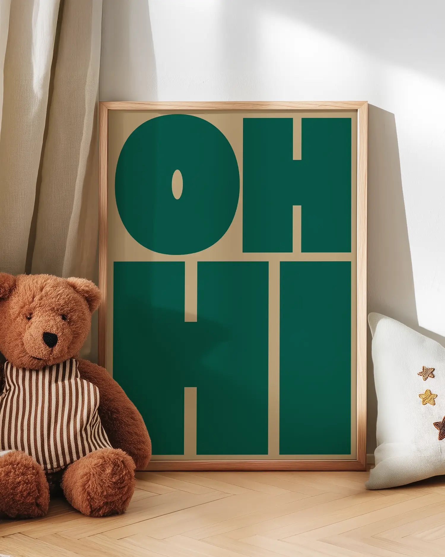 Decorative green poster with 'OH HI' text next to a teddy bear on a wooden floor.