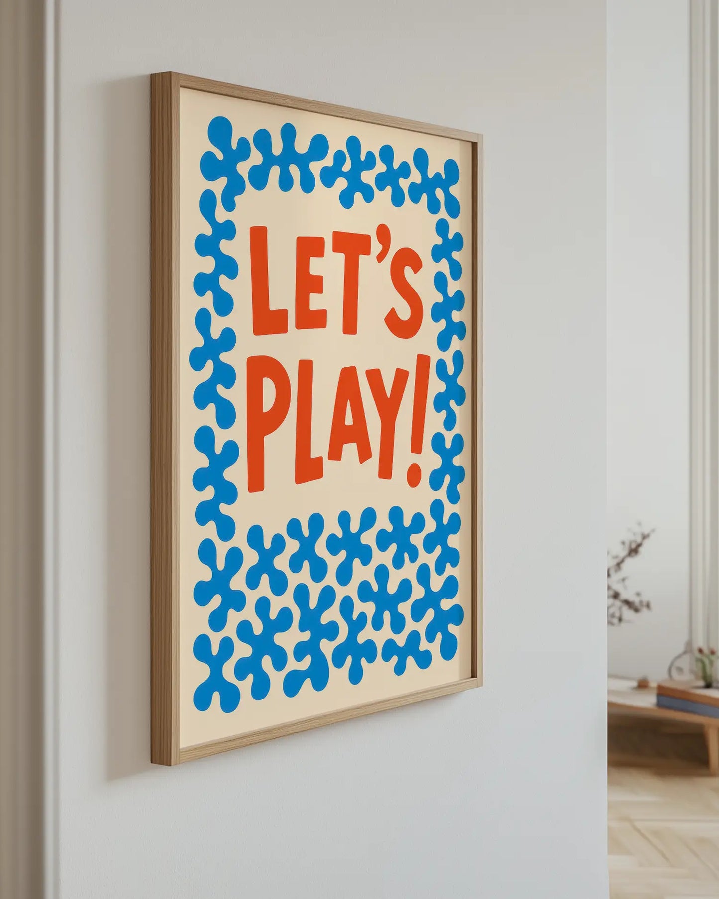 Framed artwork with 'LET'S PLAY!' text on a wall