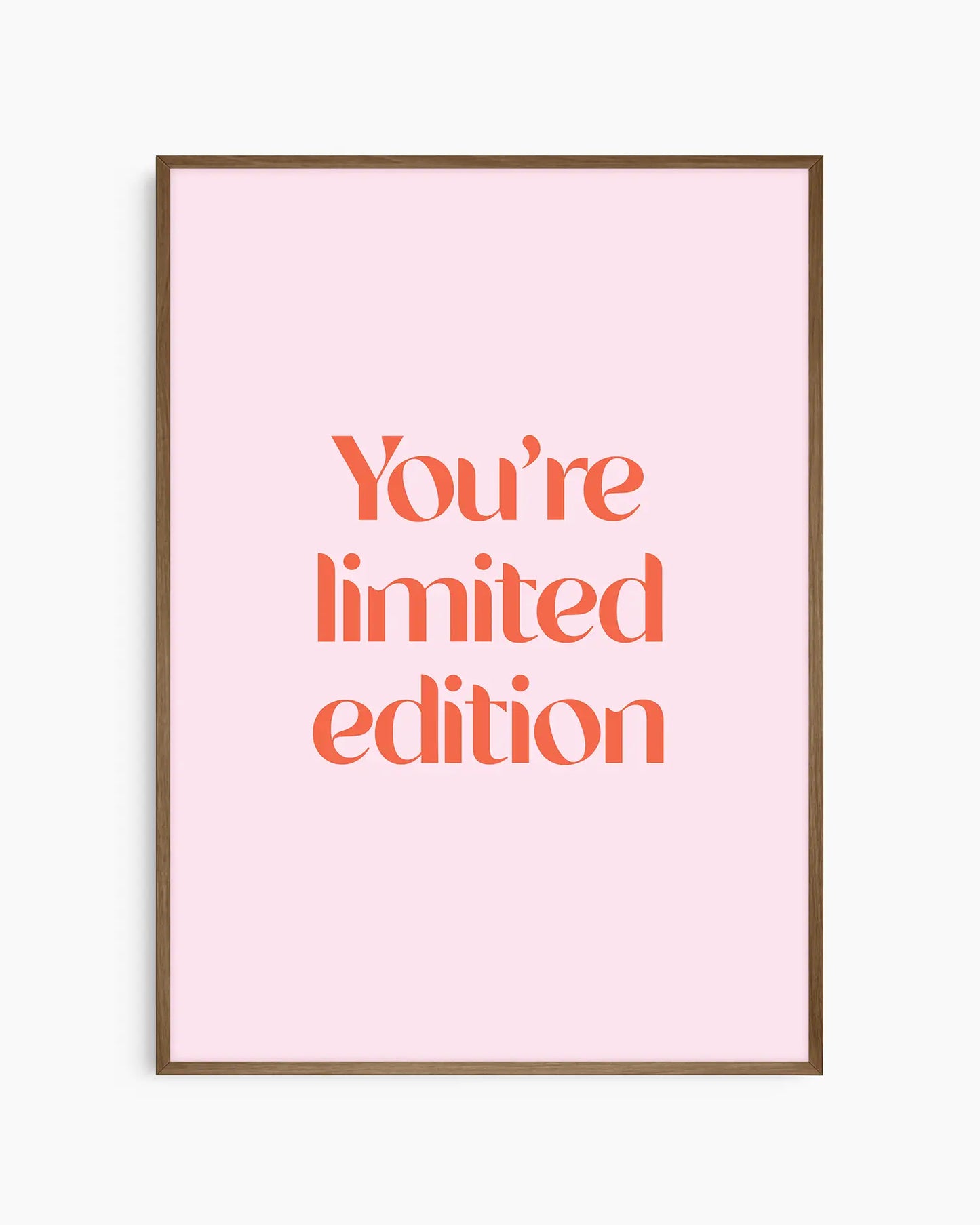 Children's poster with red text 'You're limited edition' on a pink background framed in a dark oak frame.
