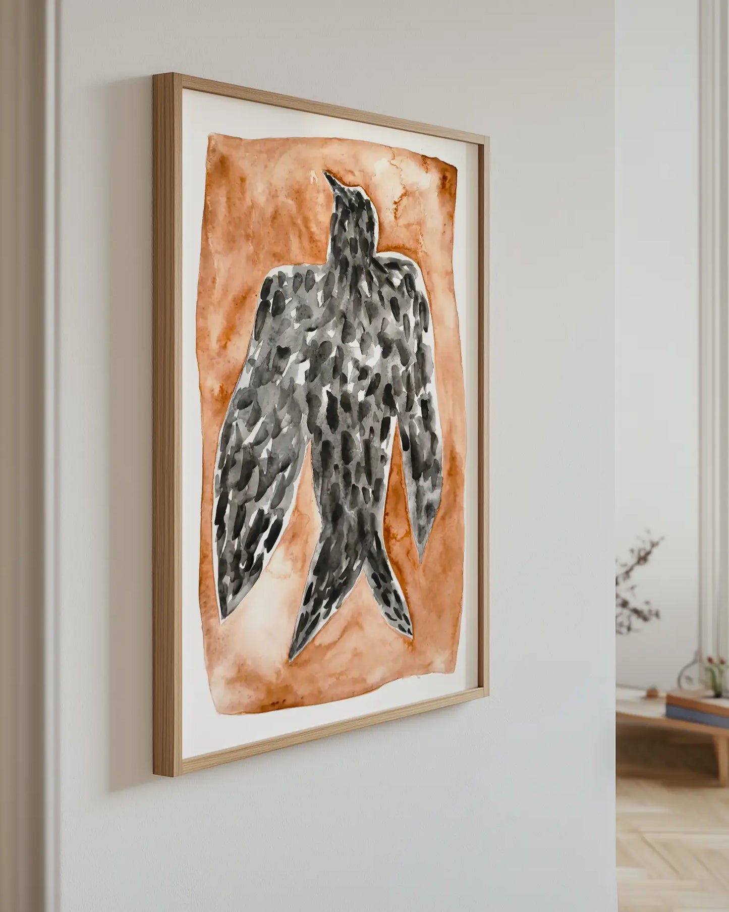 Artwork of a falcon bird on an orange background hanging on a wall.