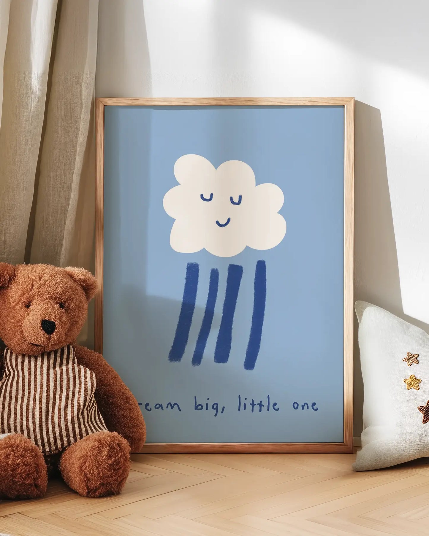 Artwork with a cloud and raindrop design next to a teddy bear on a wooden floor.