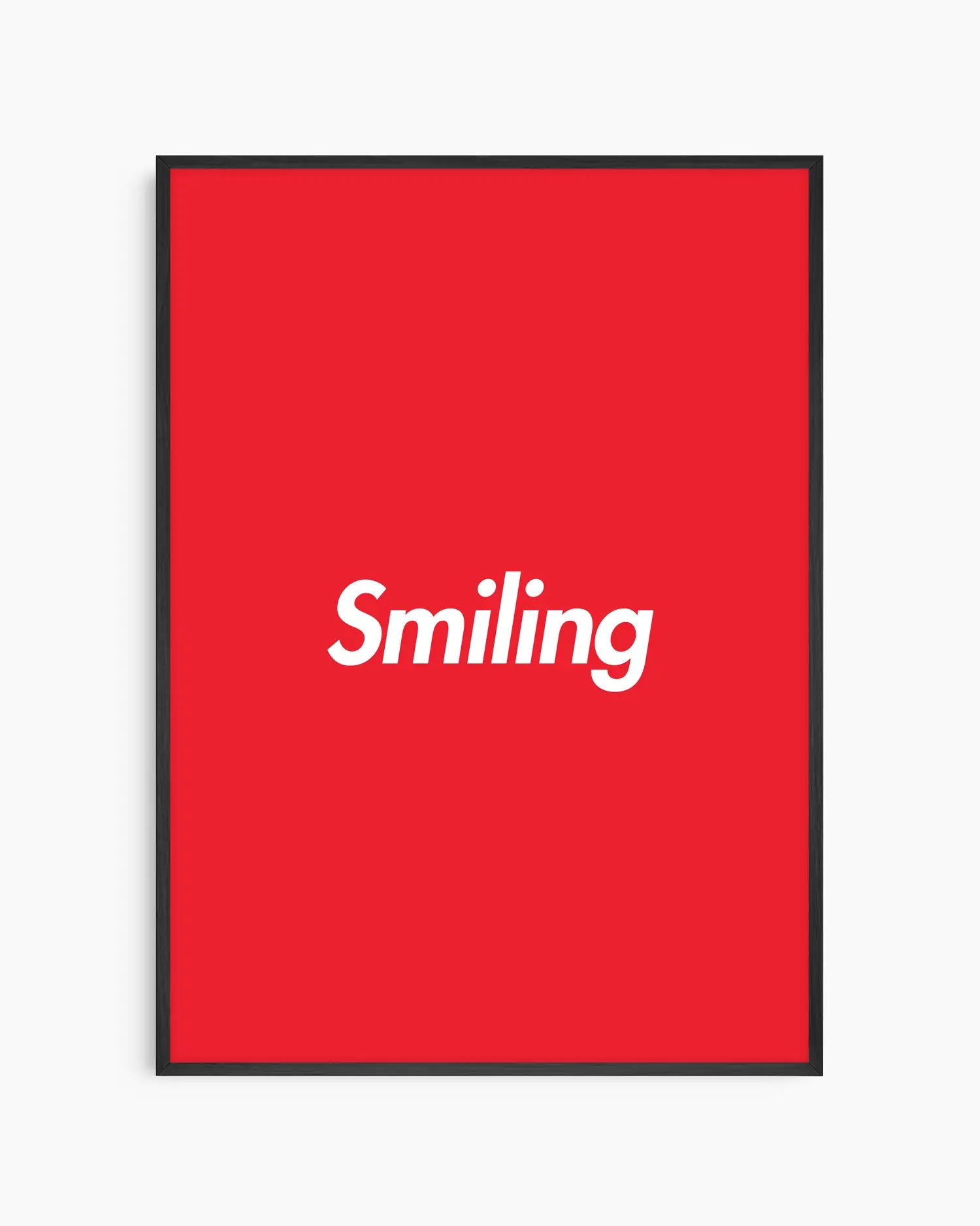 Red poster with 'Smiling' written in white, inserted in a black wooden frame.