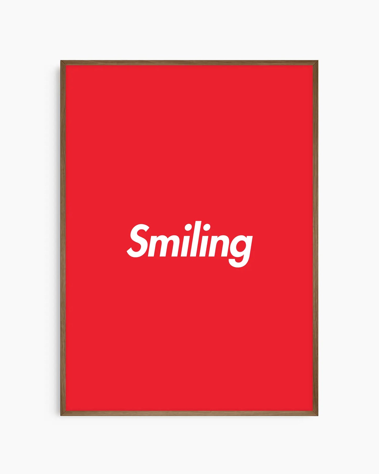 Red poster with 'Smiling' written in white, inserted in a dark oak frame.