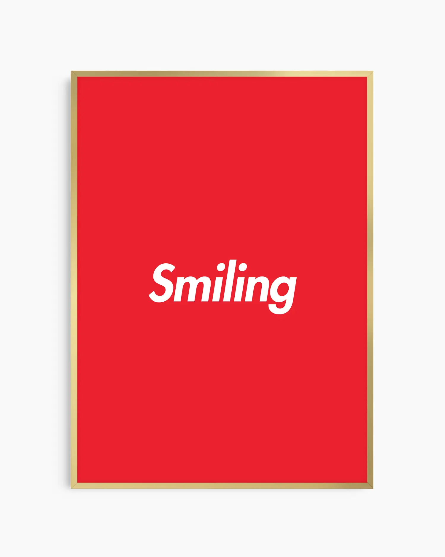 Red poster with 'Smiling' written in white, inserted in a golden aluminium frame.