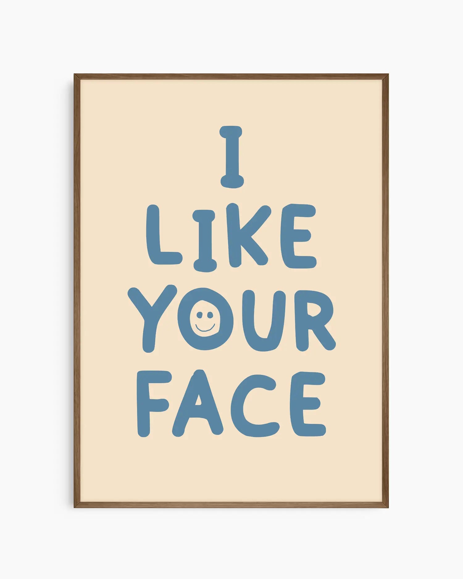 Beige nursery poster with the text 'I like your face' written in blue, framed in a smoked oak frame.