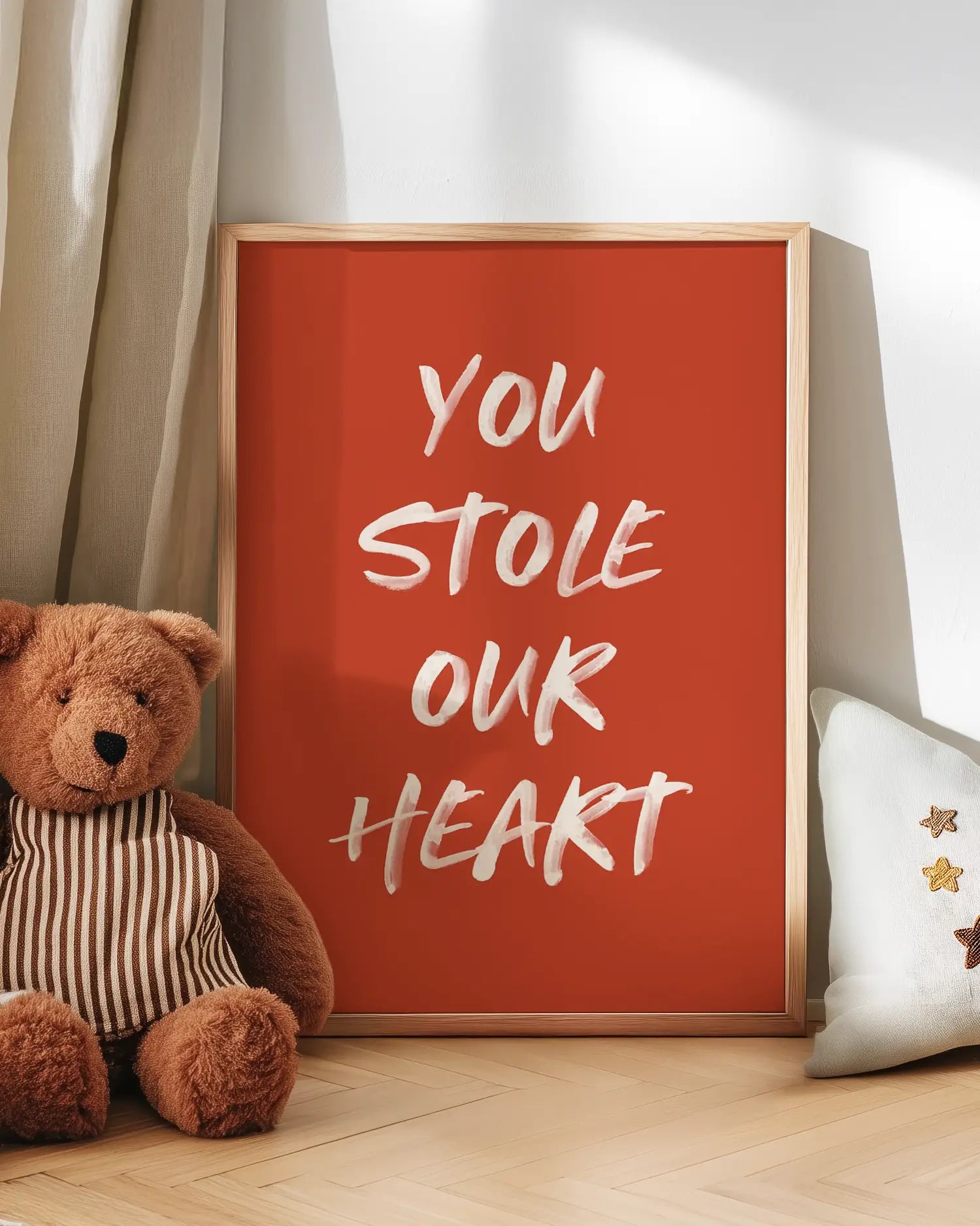 Poster with 'You Stole Our Heart' text next to a teddy bear on a wooden floor.