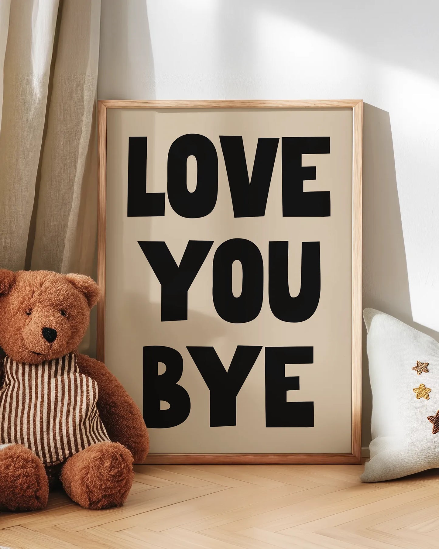 Framed sign with 'LOVE YOU BYE' text next to a teddy bear on a wooden floor.