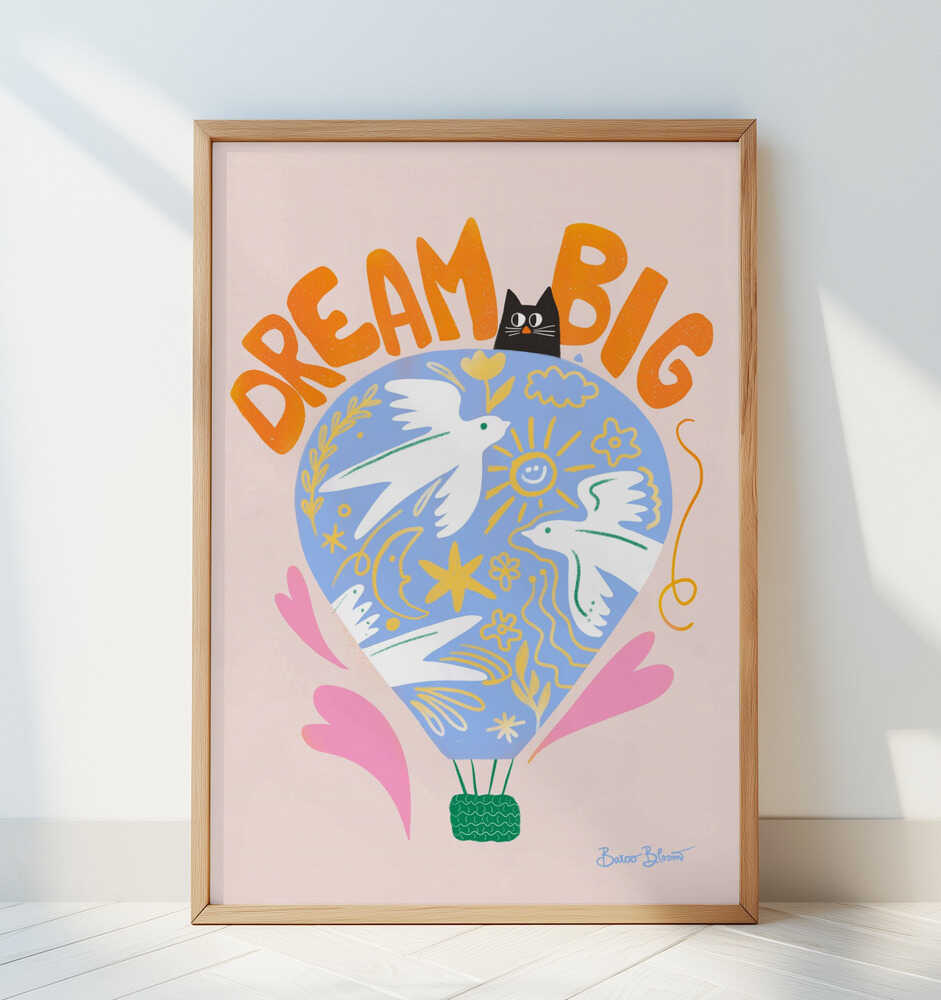 Nursery poster of a hot air ballon and the text 'Dream big' written on it. Framed and leaning against a white wall.